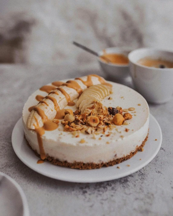 a round white cake with nuts, cinnamon and whipped cream