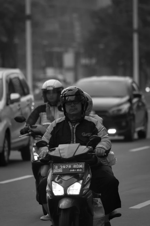 two people riding motorcycles down the street