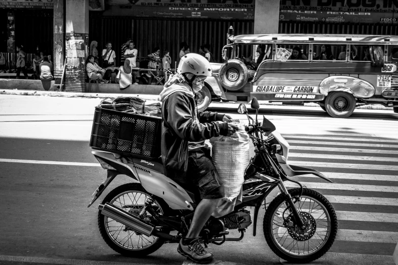 a man on a motorcycle with a bag sitting on the seat