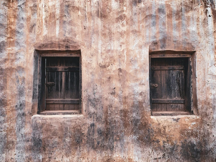 two windows in the side of an old building