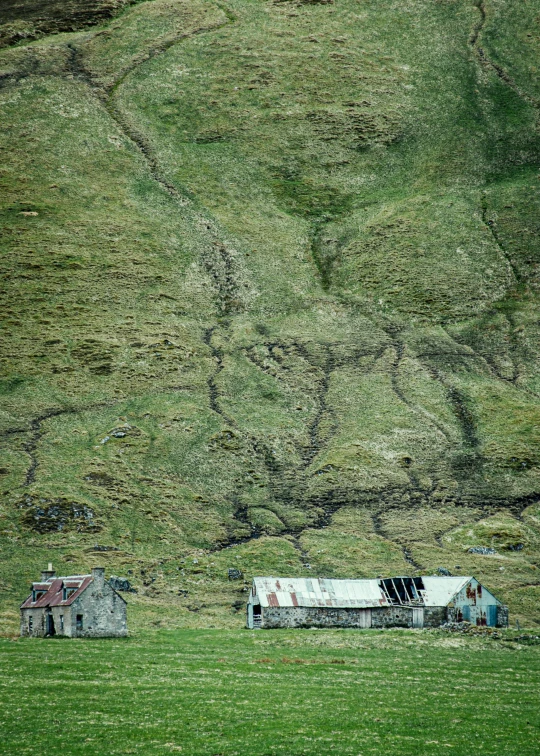 a farm house near some mountains on the hill side