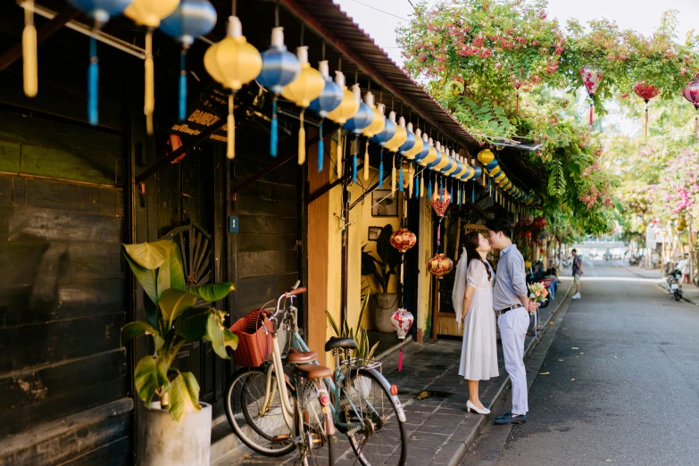 a couple are walking down the street in front of shops