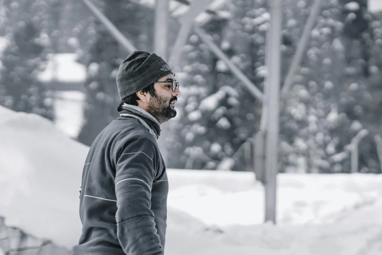 a man is standing in the snow wearing a hat