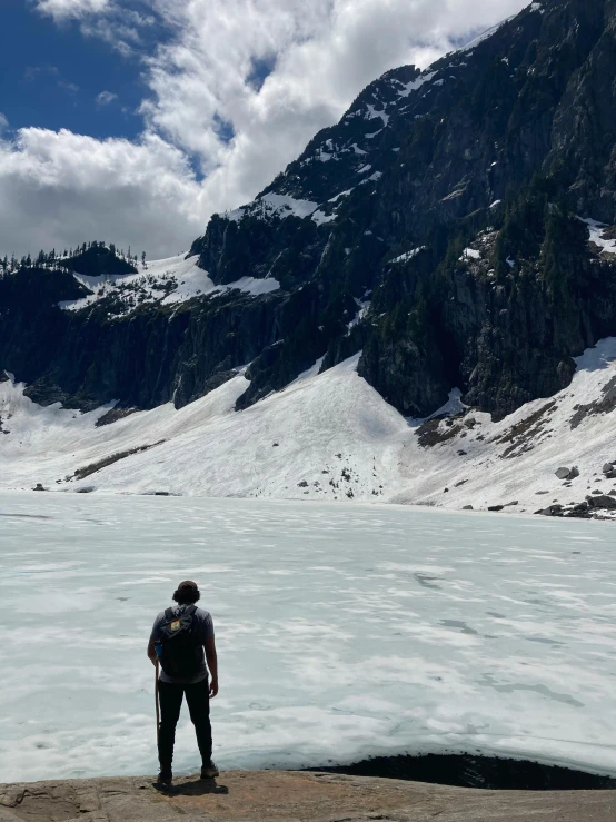 a person standing at the edge of a mountain looking out into a lake