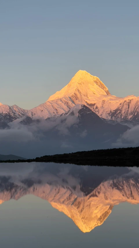 a very large snowy mountain by some water