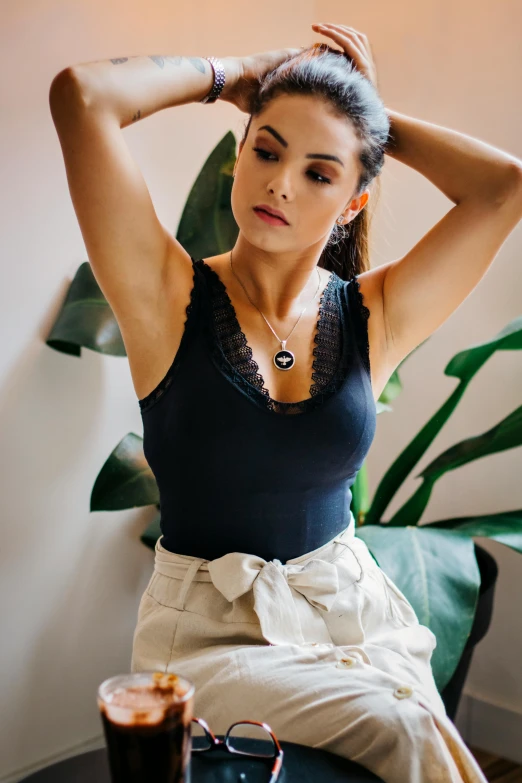 young beautiful woman sitting in front of a cup of coffee with a high bun on top