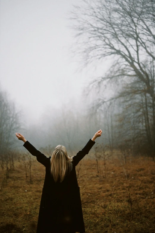 a person in a foggy field arms wide open