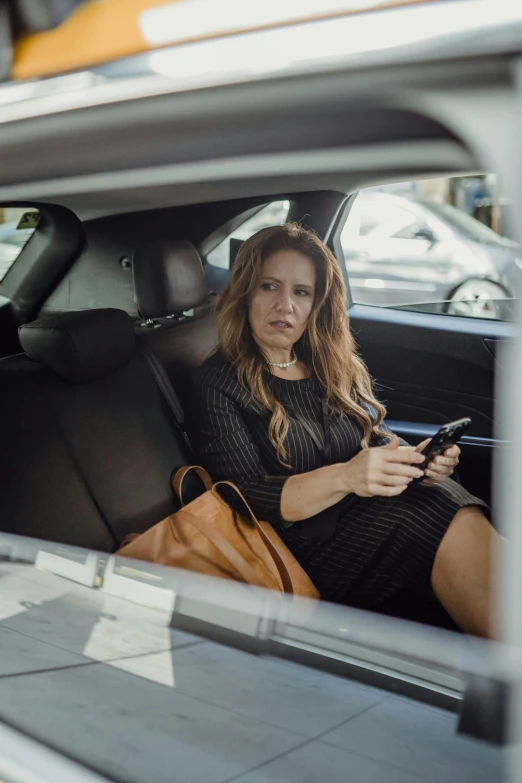 a woman sitting in her car looking at her cell phone