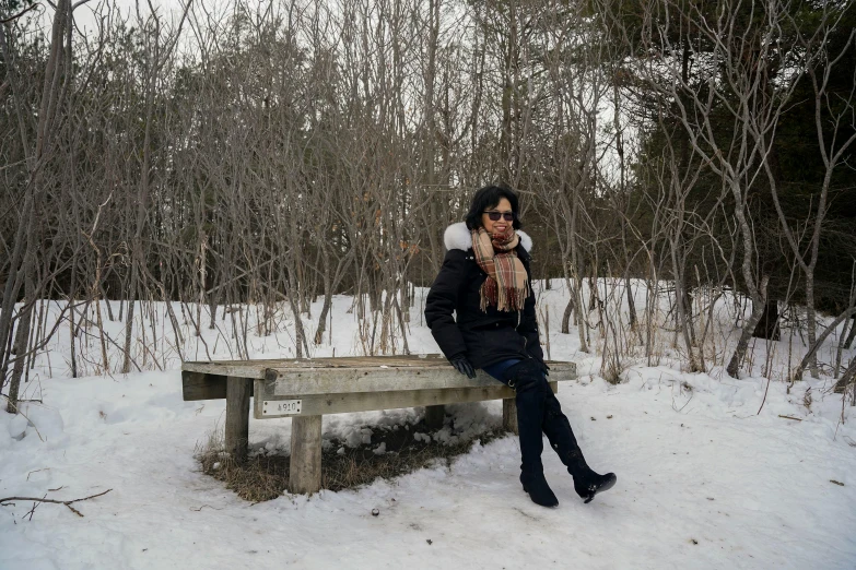 a girl with a jacket and scarf sitting on a bench