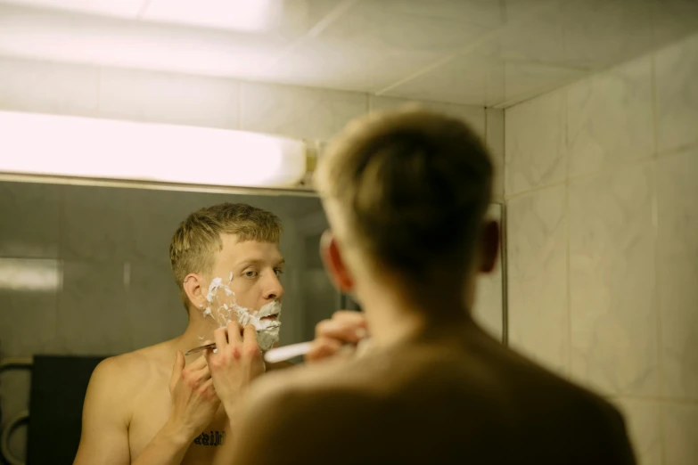 man shaving his face looking into the mirror