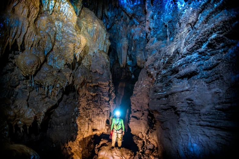 a man in yellow jacket standing in a cave