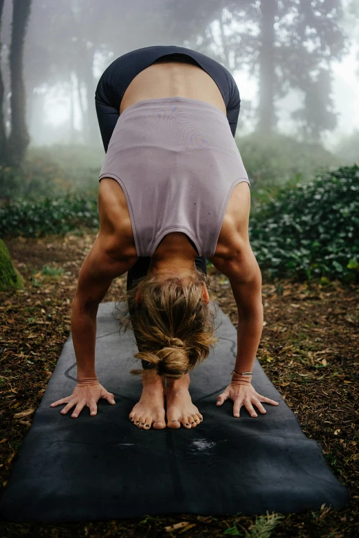 the woman is doing yoga in the woods