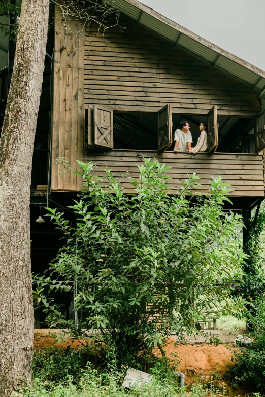 three people in an open window on a rustic house