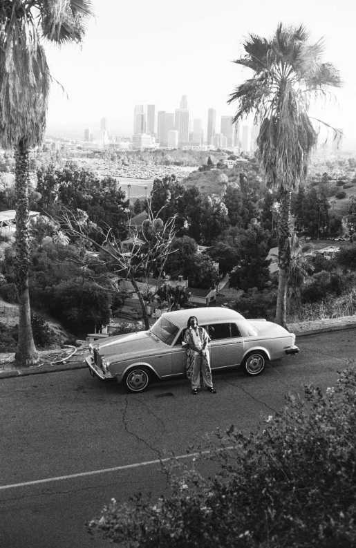 two people are standing next to a car in the road