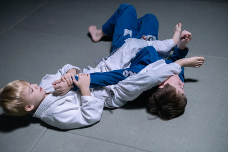 two boys are wrestling with a referee in an arena