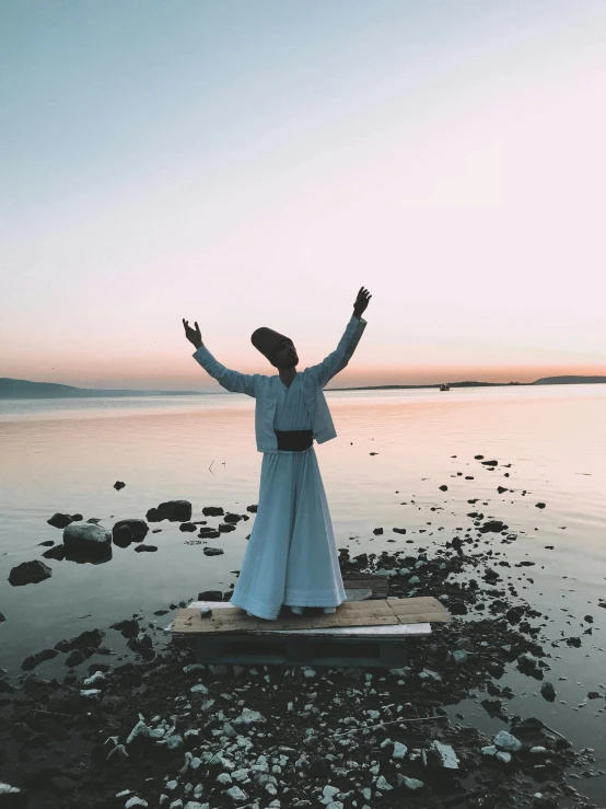 a person is standing on a small rock near the water