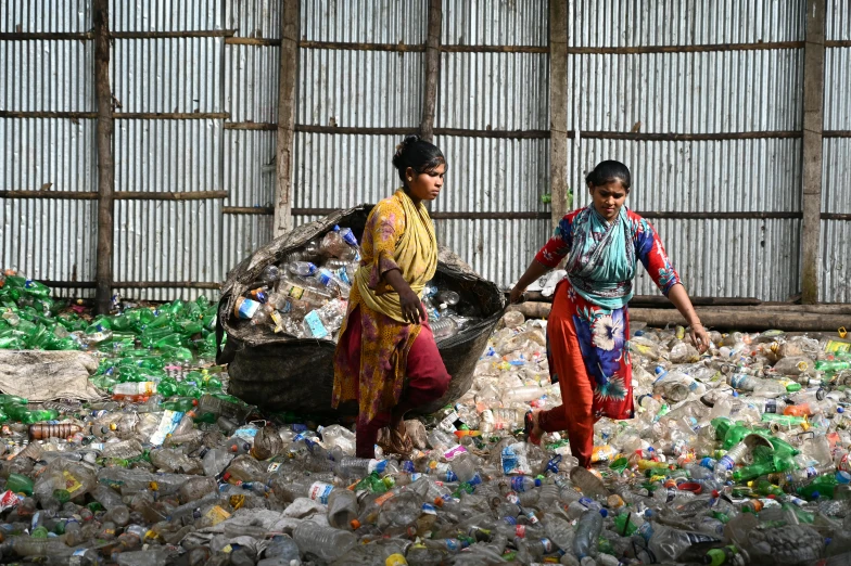 two women carrying garbage across the street