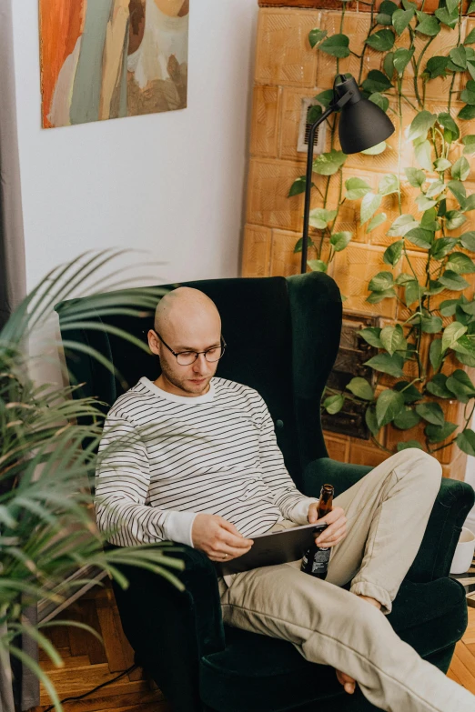 man sitting in chair in a room reading a book