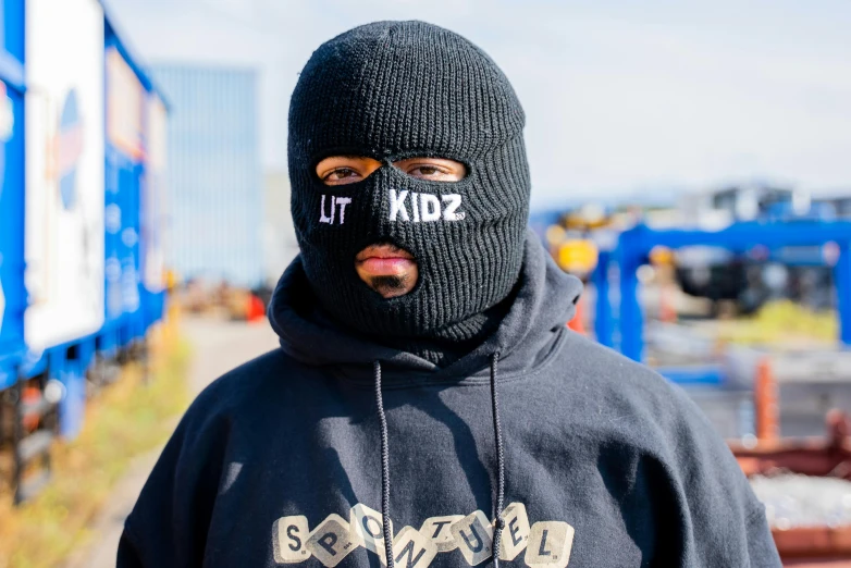 a man in a black hooded jacket has the word go hard written on his face