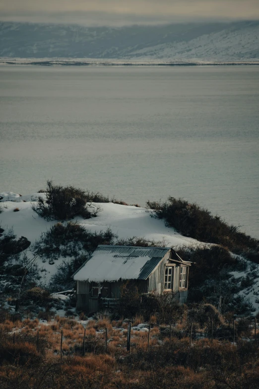 a farm house stands in the snow near the ocean