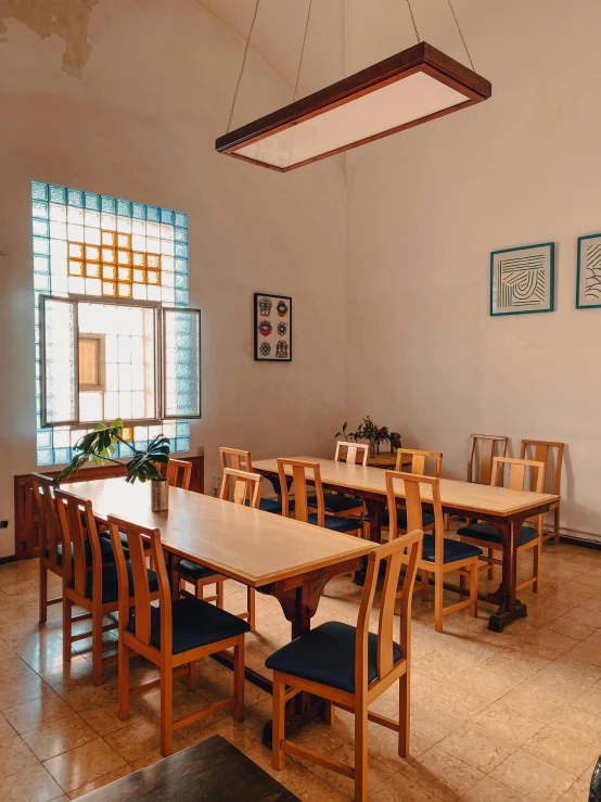 a long dining table sits between two windows with blue shades