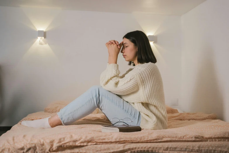 a girl sitting on top of a bed talking on the phone