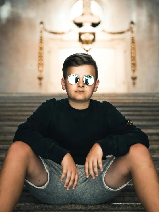 a boy sitting on the steps with his glasses on