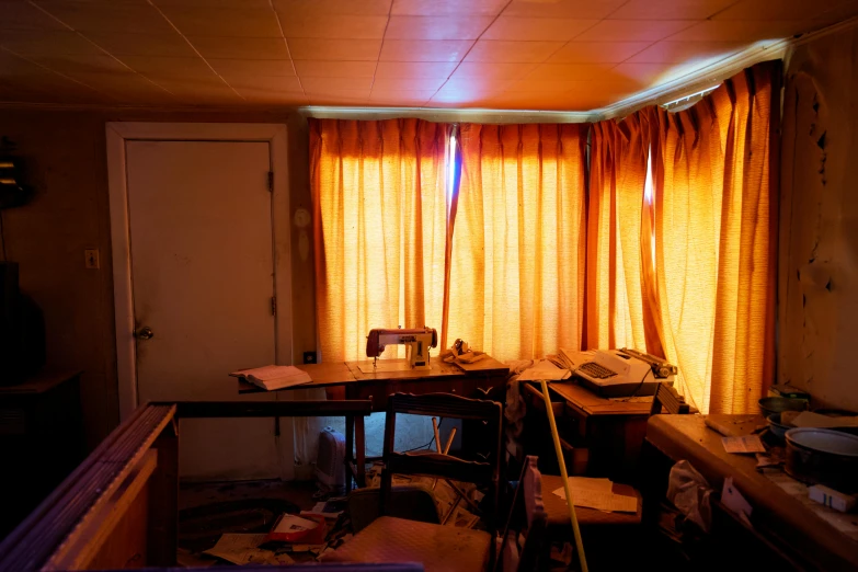 an old room with orange curtains and desk in middle