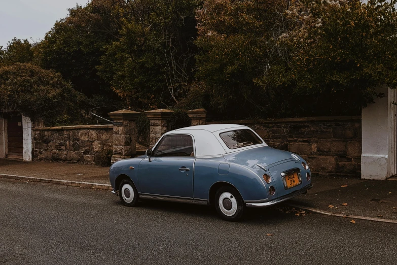 an old, blue car is parked by the side of a road