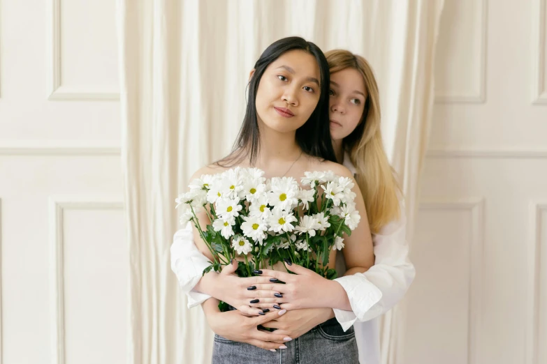 two women posing with flowers in their hands