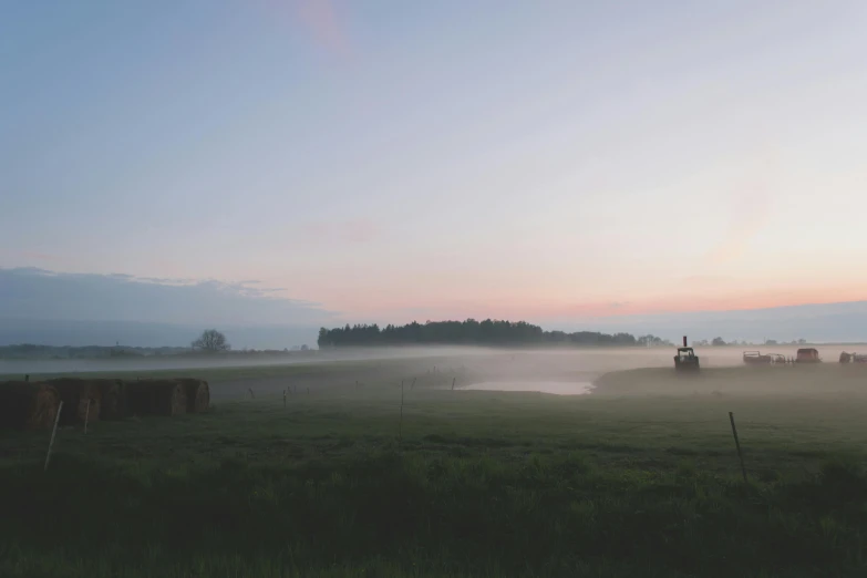 fog covers some hay and a small lake