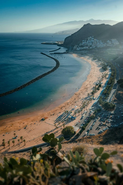 an empty beach with a large rock outcropping in the middle of the ocean