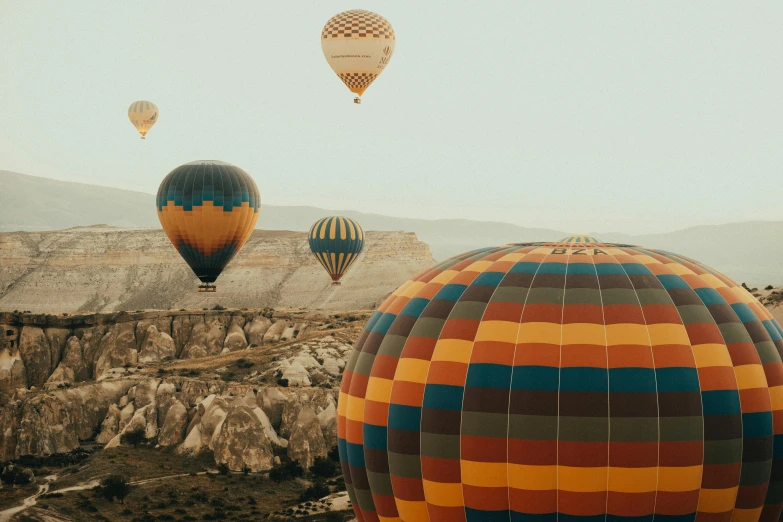 several large, multi - colored balloons being flown in the sky