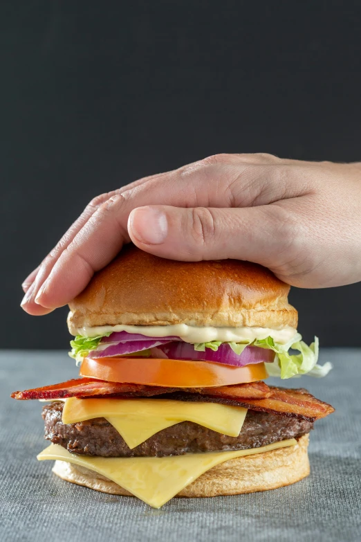 a hand is grabbing a hamburger with cheese