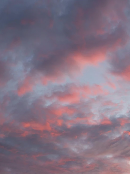 a pink and blue sky with clouds and a plane in it