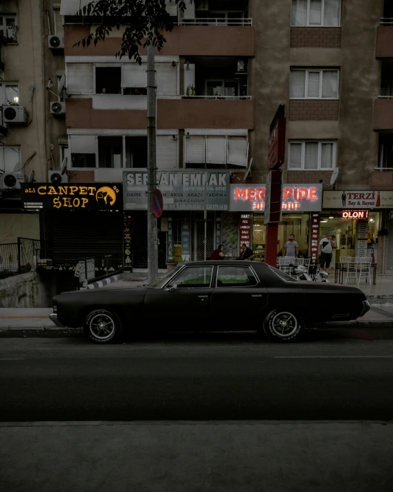 a classic car on the street in front of a business