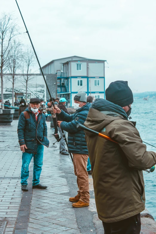 a group of people on the sidewalk with fishing rods