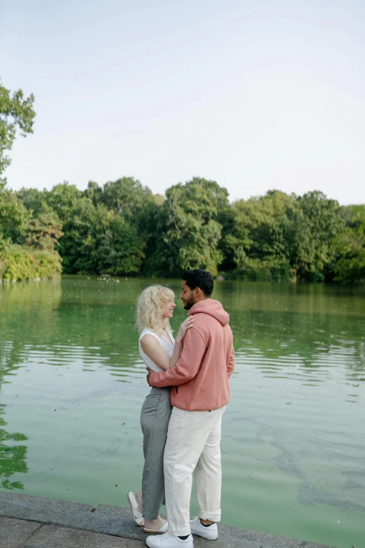 an engaged couple emce while standing on the side of the lake