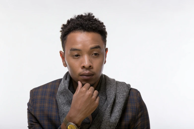 a man poses in a dark jacket and a grey scarf