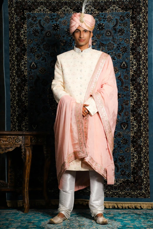 man in traditional indian clothing standing against a wall