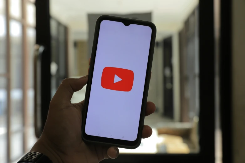 someone holding a smartphone with youtube on the screen