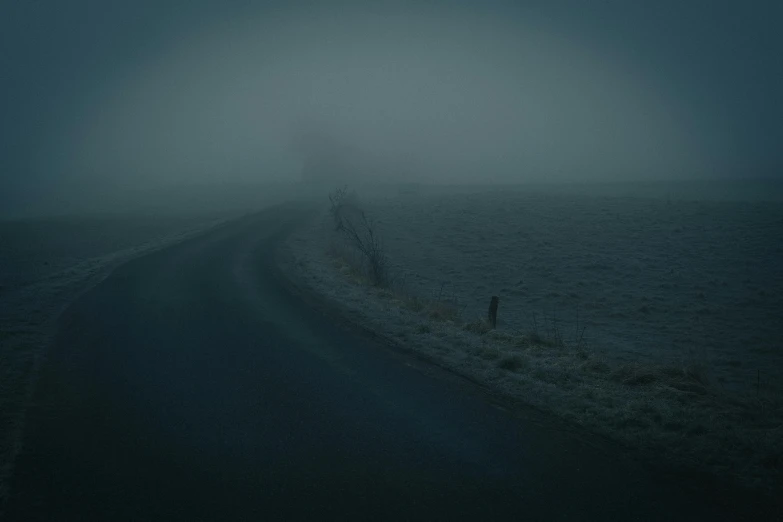 a dark dark night with a person standing alone on a road