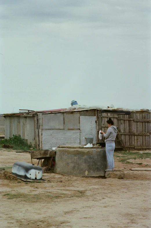 a woman standing outside a shack with two boats