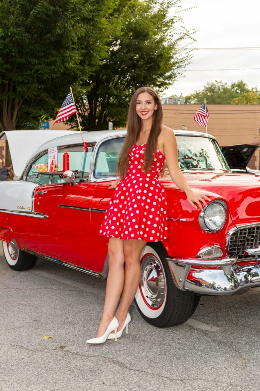 woman leaning on red car with flag at rear end