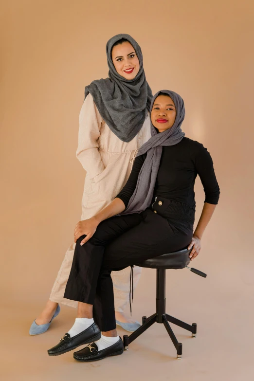 two women are sitting down, one is posing for the camera