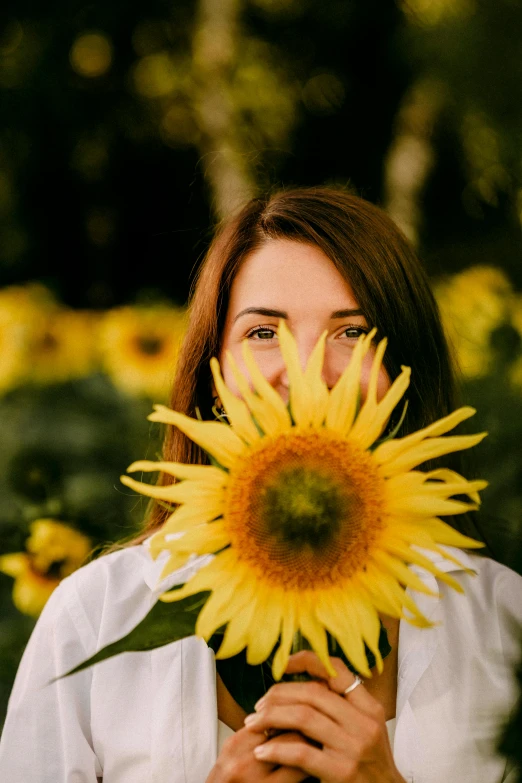 the woman is holding a yellow flower with her eyes closed