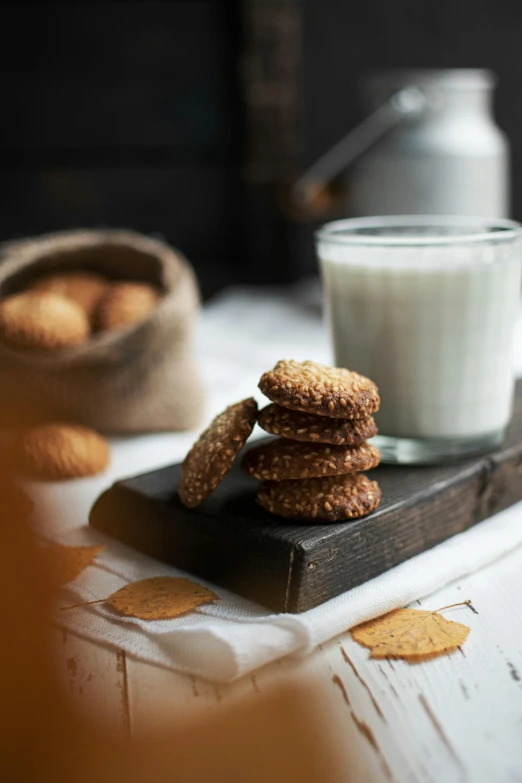 four cookies and a glass of milk sit on the edge of a table