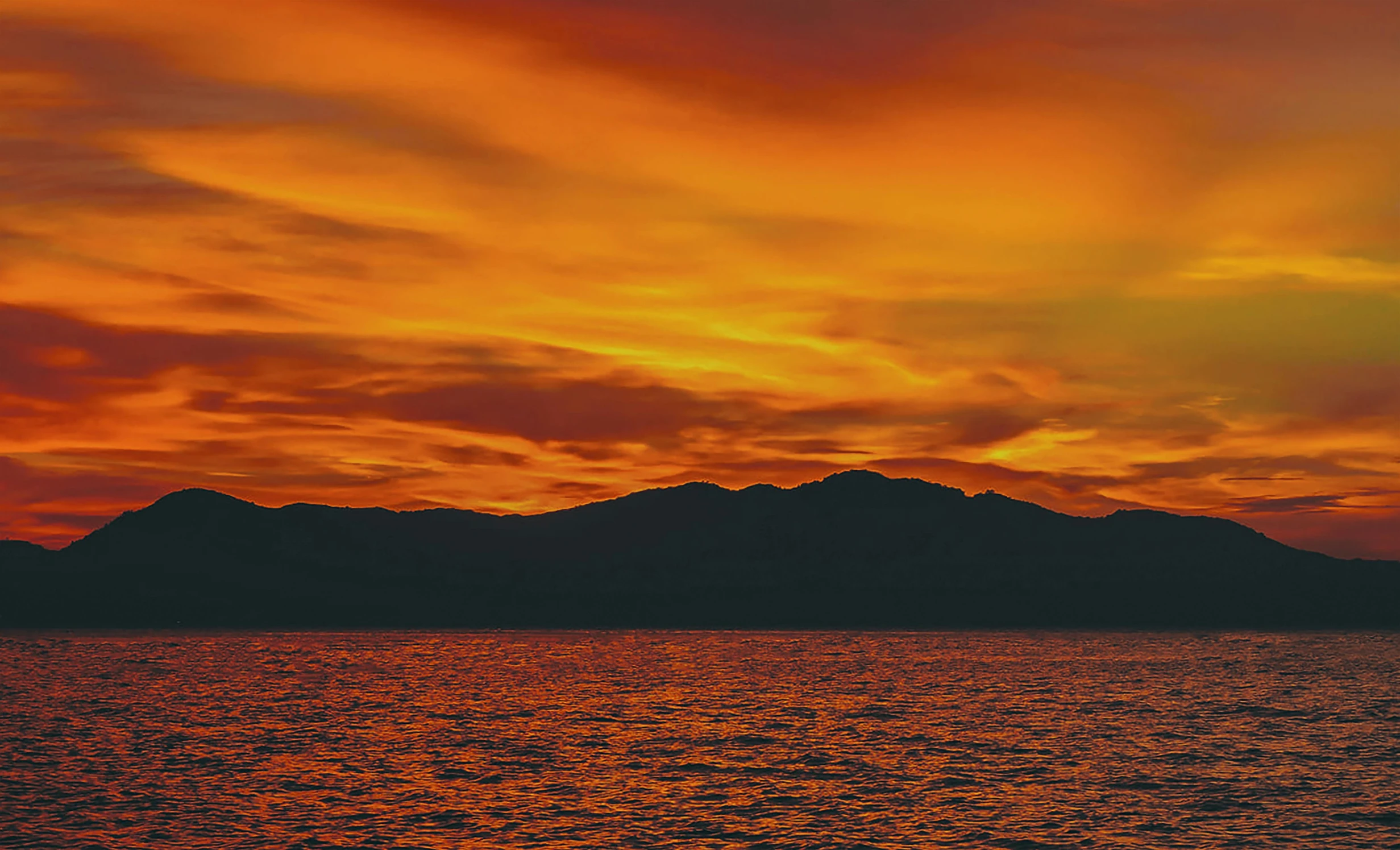 an orange and pink sky over a calm ocean