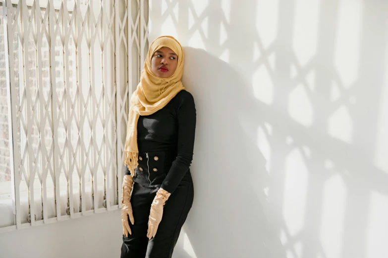 a woman wearing black jumpsuit leaning against a wall