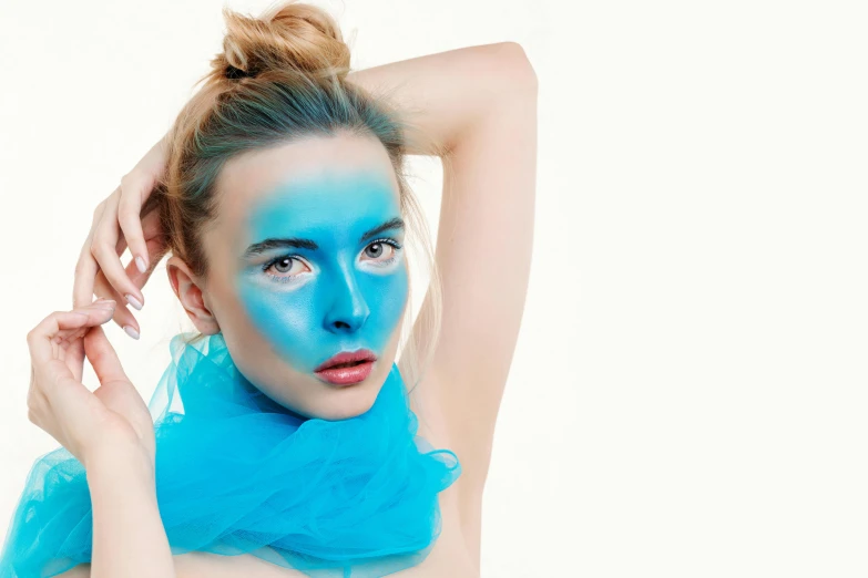 a beautiful young lady with blue make up holding her hair to the side